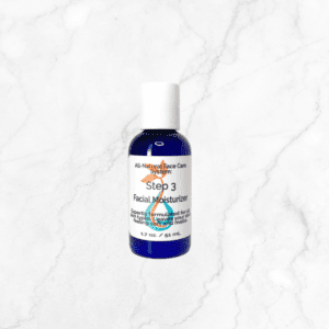 A blue bottle of Face Moisturizer labeled "Step 3 Facial Moisturizer" with a white cap sits on light gray marble. This 1.7 oz (51 ml) hydrating lotion offers all-natural face care.