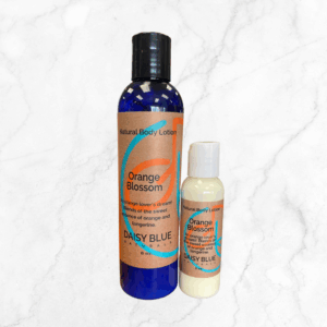 Two bottles of Orange Blossom Lotion—a large blue bottle and a small white one, each with orange labels—are shown on a light marble background.