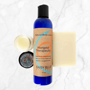 The Skin / Eczema Trio—Marigold Lotion, Marigold Salve, and Purely Soap—is beautifully arranged on a white marble surface.