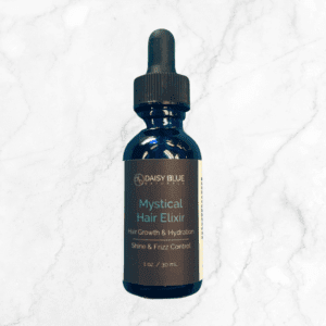 A blue glass dropper bottle labeled "Mystical Hair Elixir" for hair growth, hydration, shine, and frizz control rests on a light marbled surface next to the Liquid Quartz Face Serum.