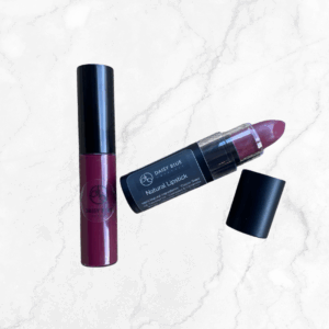 The Wine Not & Purely Plum Lipstick & Lip Gloss Duo sits on a white marble surface, with the lip gloss closed and the lipstick open beside its cap—a perfect pairing for your lips.