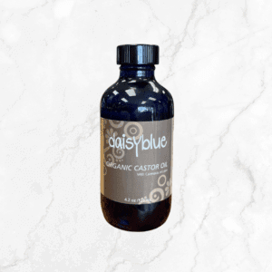 A dark blue glass bottle with a black cap labeled "Organic Castor Oil with Calendula, 4.2 oz / 125 ml" sits on white marble, showcasing the nourishing blend of calendula and organic castor oil.