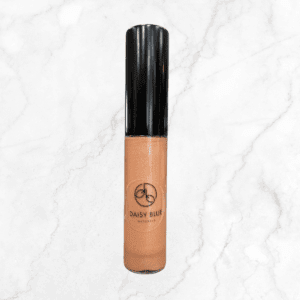 A Charcoal Mist Eyeshadow compact rests on a white marble background, its smoky shade pairing perfectly with nude, shimmery lip gloss for a subtle, elegant look.